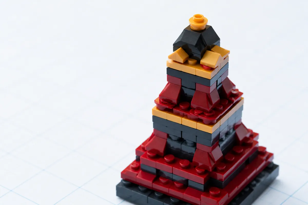 A close-up of a tiered red, black, and gold brick-built pagoda-style tower structure.